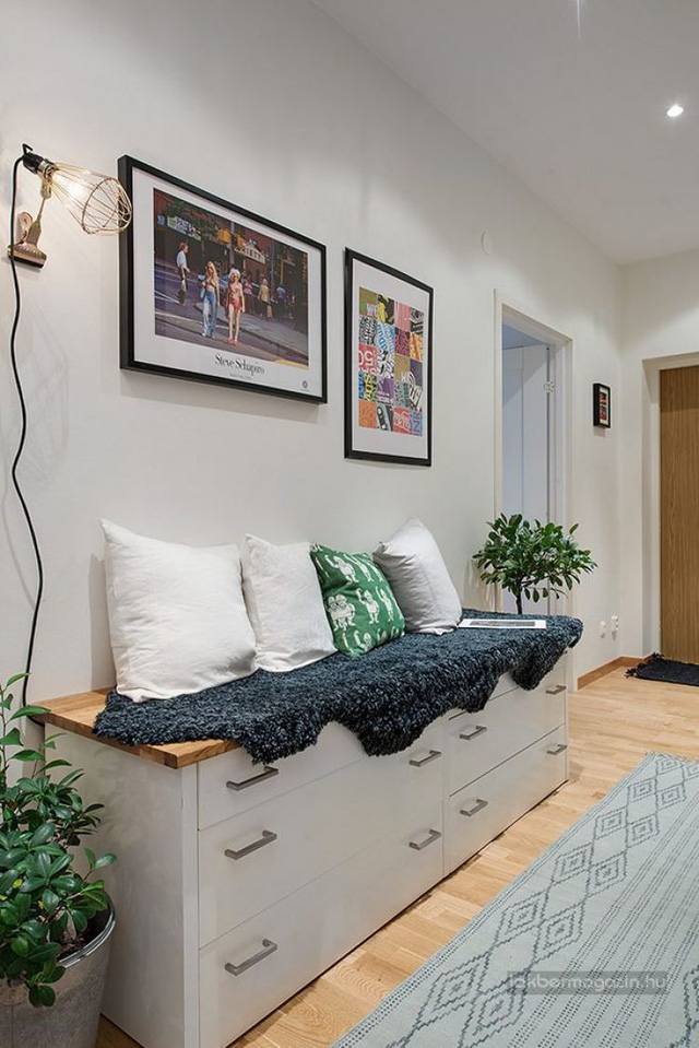 Lối vào nhà được trang trí đẹp mắt với những bức tranh treo tường và chậu cây xanh mang không gian tươi mát cho ngôi nhà. Dọc tường chủ nhà còn đặt một hệ tủ kệ đa năng làm nơi trữ đồ lý tưởng. 